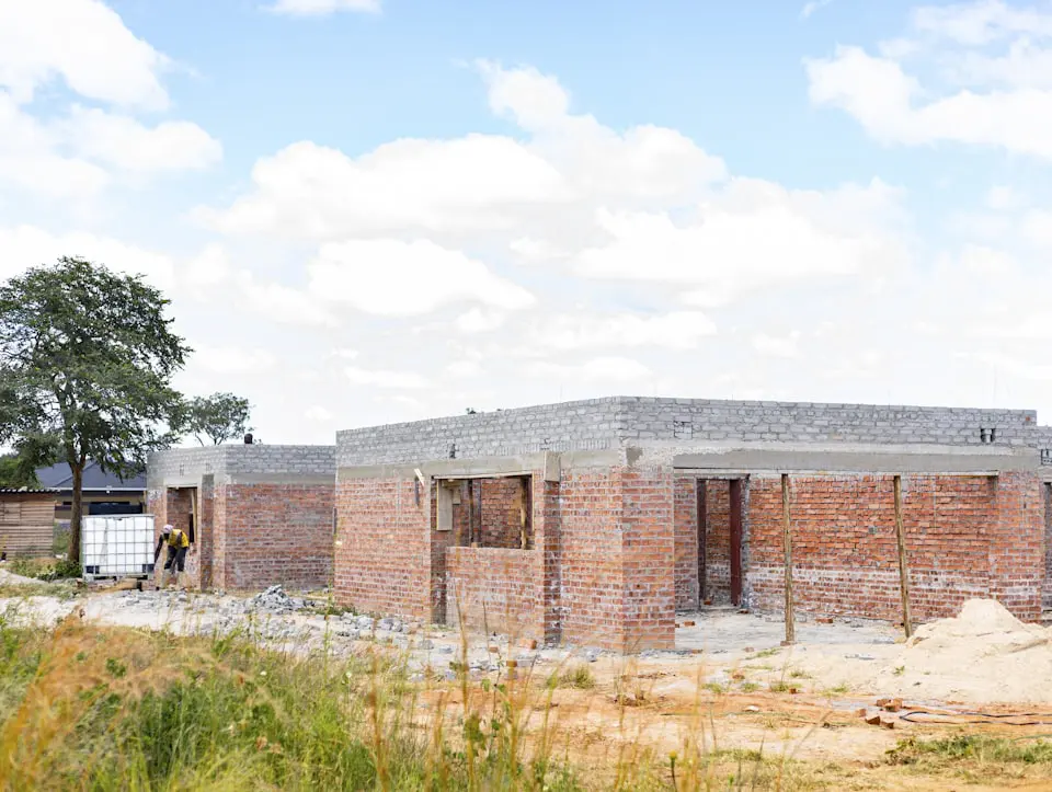 A red brick house shell under construction on a sunny day with openings framed out