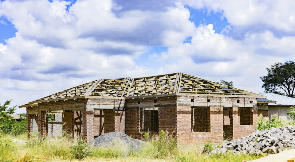 A single storey brick house under construction with its timber roof trusses standing