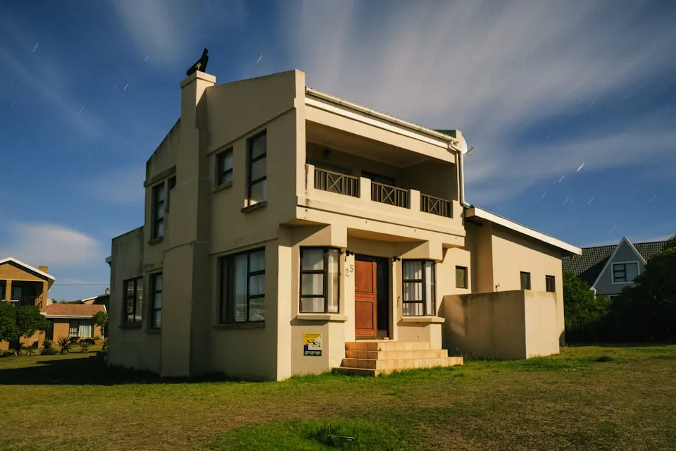 A finished two storey plastered house with a tiled roof seen from the street