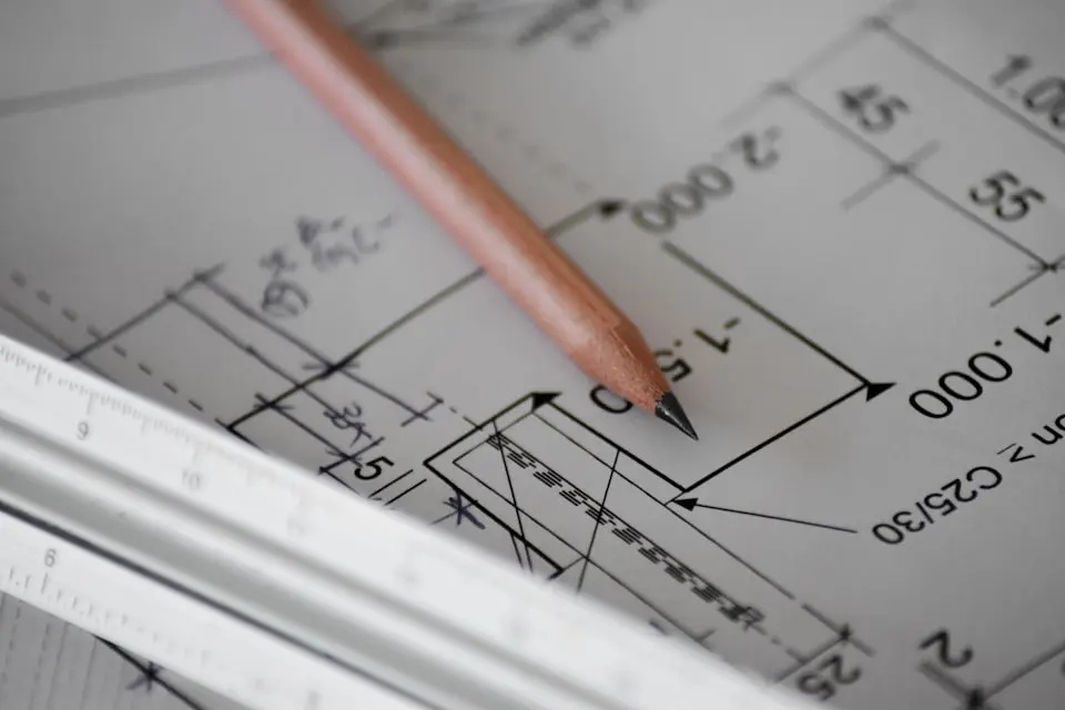 A pencil resting on a dimensioned technical drawing showing setting-out measurements